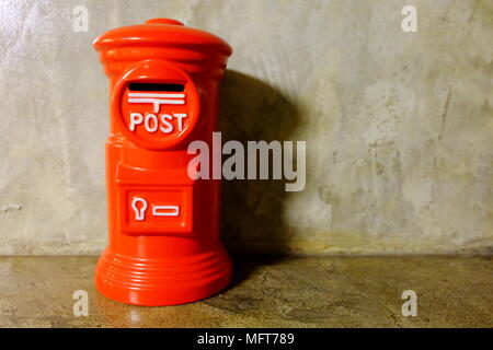 Red Post Office Box Risparmio su sfondo di calcestruzzo. Foto Stock