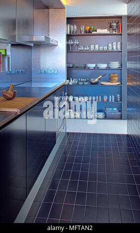 Costruito in scaffali possono essere nascoste dietro la porta scorrevole in stretta moderna cucina con piastrelle blu a parete e a pavimento Foto Stock