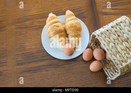 Cornetti e rosolare le uova nel paniere pronto per una sana prima colazione Foto Stock