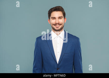 Bel giovane imprenditore toothy sorridente. La gente di affari concetto, riccamente e successo. Indoor, studio shot su fondo azzurro Foto Stock