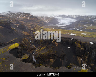 Profondo canyon in volcanic Islanda paesaggio con montagne e il ghiacciaio Solheimajokull in background Foto Stock