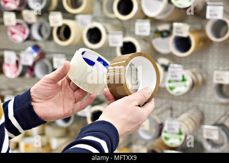 L'uomo acquirente sceglie l'adesivo del nastro per condotti in negozio Foto Stock