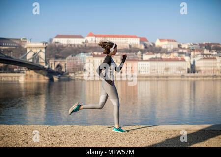 Piuttosto giovane atleta femminile in esecuzione sul lungomare a Budapest, Ungheria Foto Stock