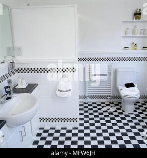 Bagno moderno con in bianco e nero di piastrelle a scacchi lavandino WC e scaffalature di nicchia. Foto Stock