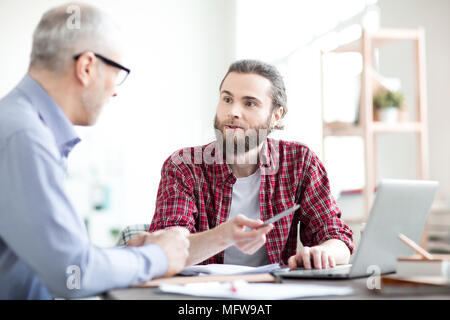 Business i colleghi seduti a tavola e utilizzando laptop insieme in team Foto Stock