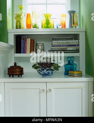 Vetreria colorati visualizzati in bianco unità di armadio con ripiani Foto Stock