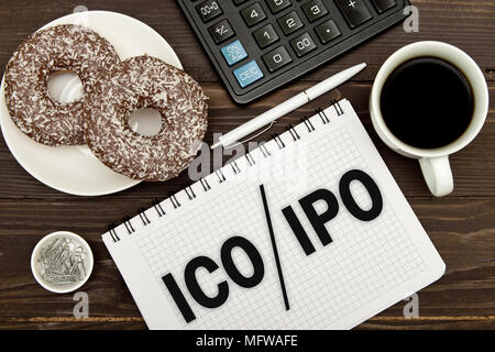 Notebook con un Business note ICO iniziale offerta di moneta vs IPO Offerta pubblica iniziale sull'ufficio tavolo con gli attrezzi. Concetto ipo e ICO Foto Stock