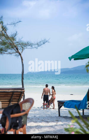 Candide colpo di una giovane coppia di parlare su una spiaggia di sabbia bianca su di un isola nel sud-est asiatico Foto Stock