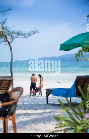 Candide colpo di una giovane coppia di parlare su una spiaggia di sabbia bianca su di un isola nel sud-est asiatico Foto Stock