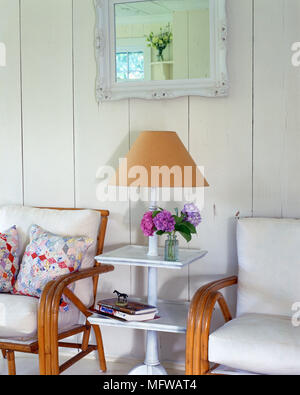 La Lampada sul tavolo bianco tra due sedie di canna con cuscini Foto Stock