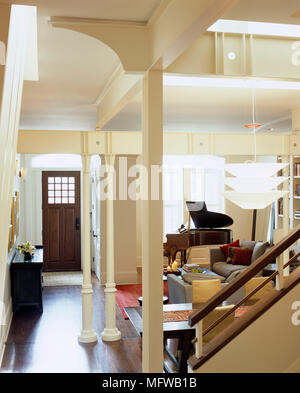 Open plan room con la parte anteriore della porta d'ingresso che conduce nella zona salotto con pianoforte Foto Stock