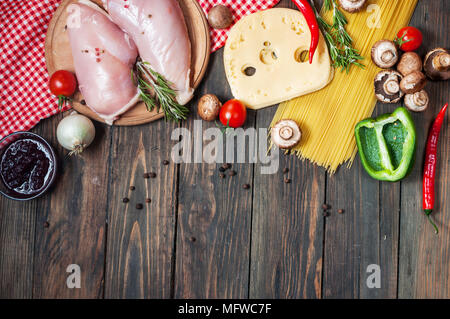 Ingredienti per la pasta. Cherry-pomodori, spaghetti, Filetto di pollo e funghi sul tavolo di legno Foto Stock