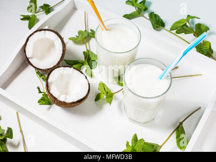 Noce di cocco latte vegano coctail in vetro su sfondo di legno. Foto Stock