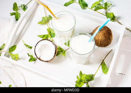 Noce di cocco latte vegano coctail in vetro su sfondo di legno. Foto Stock