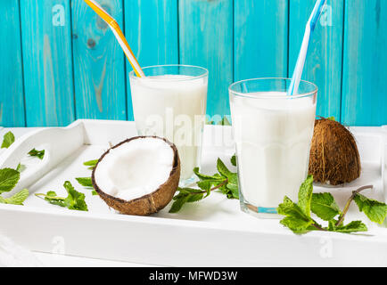 Noce di cocco latte vegano coctail in vetro su sfondo di legno. Foto Stock