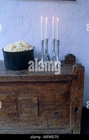 Candele accese in metallo su candelabri in legno rustico petto Foto Stock