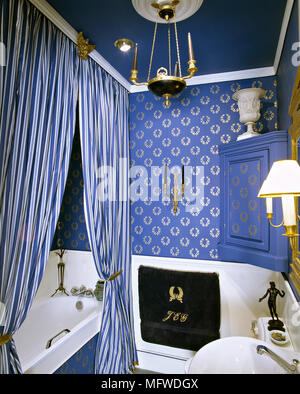 Bagno blu con carta da parati di pattern, vasca nascosta da motivo rigato tenda, Foto Stock