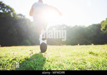 Outdoor cross-country in esecuzione in un sole estivo nozione di esercizio, fitness e uno stile di vita sano. In prossimità dei piedi di un uomo che corre in erba Foto Stock