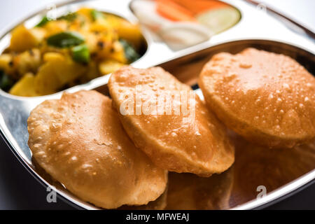 , Aloo RFI o Bombay patate e puri/Poori in un acciaio inossidabile targhetta ovale, il fuoco selettivo Foto Stock