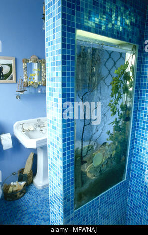 Bagno moderno dettaglio con vetro blu pareti di piastrelle e pavimento, built-in vasca e lavandino a colonna. Foto Stock