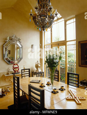 Lampadario ornato di legno sopra un tavolo da pranzo e sedie Foto Stock