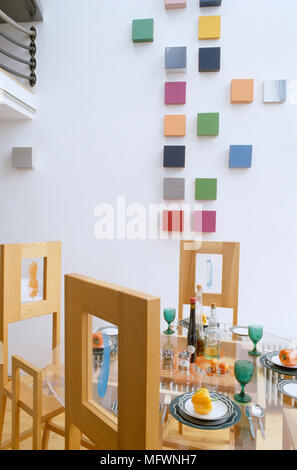 Sedie di legno intorno al ripiano in vetro tavolo da pranzo prevista per la cena in contemporanea sala da pranzo Foto Stock