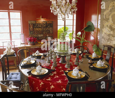 Lampadario in vetro sopra tavola rotonda impostata per la cena in rosso la sala da pranzo Foto Stock