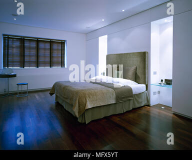 Camera da letto minimalista con letto matrimoniale con testata rivestita  accanto all'alcova e poltrona la finestra di fronte Foto stock - Alamy