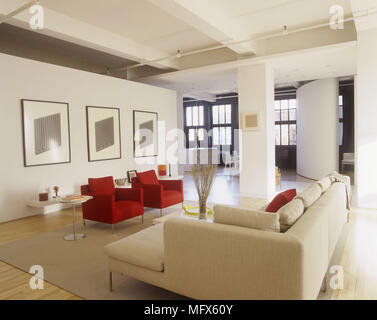 Un moderno e minimalista piano aperto salotto con poltrone rosse folle Divano Vista della sala da pranzo Foto Stock