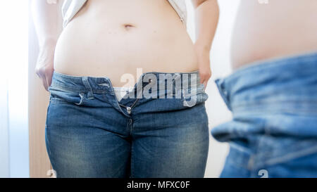 La donna caucasica con grande pancia indossare jeans stretti in spogliatoio Foto Stock