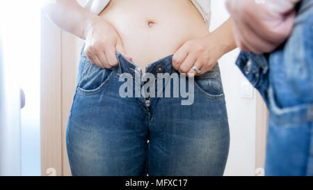 Primo piano della giovane donna obesa cercando di montare in jeans stretti Foto Stock