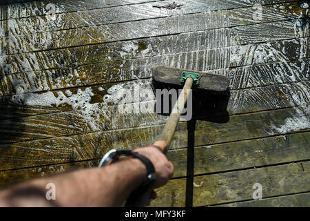 Verde e sporchi coperti di alghe giardino decking in procinto di essere puliti con detergente chimico. Foto Stock