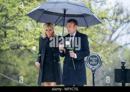 Il Presidente francese Emmanuel Macron, destro e da sua moglie Brigitte Macron, luogo unico rose bianche sul recinto dell ex Presidente John F. Kennedy e Jacqueline Bouvier Kennedy Onassis in una piovosa giornata presso il Cimitero Nazionale di Arlington, Aprile 24, 2018 in Arlington, Virginia. Foto Stock