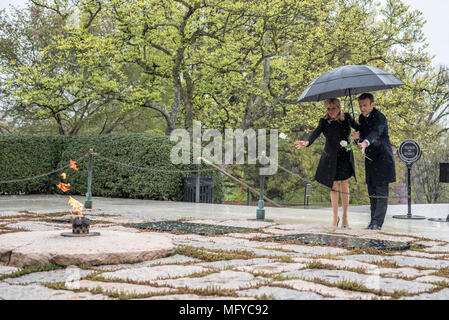 Il Presidente francese Emmanuel Macron, destro e da sua moglie Brigitte Macron, luogo unico rose bianche sul recinto dell ex Presidente John F. Kennedy e Jacqueline Bouvier Kennedy Onassis in una piovosa giornata presso il Cimitero Nazionale di Arlington, Aprile 24, 2018 in Arlington, Virginia. Foto Stock