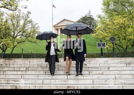 Il Presidente francese Emmanuel Macron, destro e da sua moglie Brigitte Macron, sono scortati dalla soprintendente Katharine Kelley, sinistra, durante una visita al recinto dell ex Presidente John F. Kennedy e Jacqueline Bouvier Kennedy Onassis in una piovosa giornata presso il Cimitero Nazionale di Arlington, Aprile 24, 2018 in Arlington, Virginia. Foto Stock
