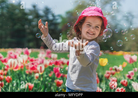 Una bambina soffiando bolle di sapone in estate park. Foto Stock