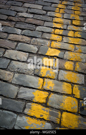 Strisce gialle dipinta su una strada acciottolata Foto Stock