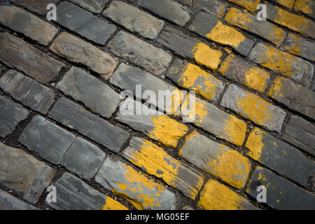 Strisce gialle dipinta su una strada acciottolata Foto Stock