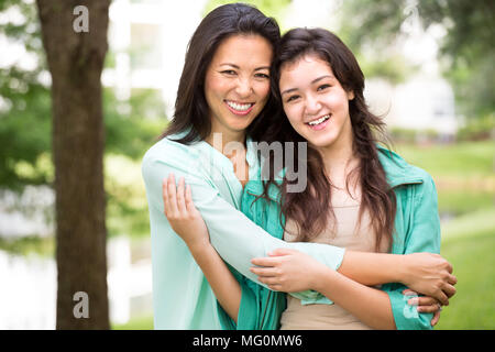 Asian madre ridendo e huging il suo bambino. Foto Stock