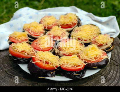 Grigliata di fette di melanzana con pomodoro e salsa piccante e formaggio grattugiato Foto Stock