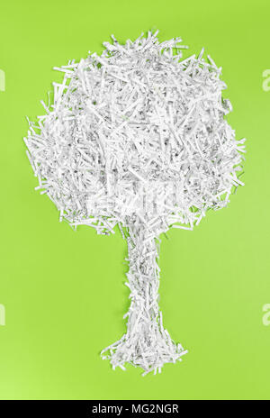 Tree fatta di carta tagliuzzata, luminoso su sfondo verde. Il riciclaggio e l'ambiente il concetto di protezione. Foto Stock