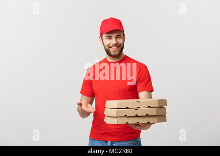 Concetto di consegna: giovani caucasici bello Pizza consegna uomo con scatole per pizza isolate su uno sfondo grigio Foto Stock