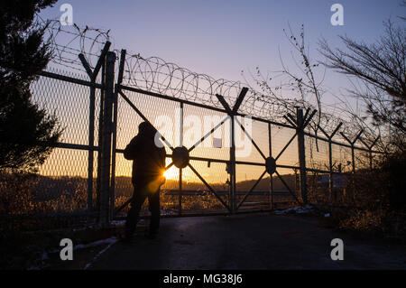 Un uomo guarda nella zona demilitarizzata tra la Corea del Nord e la Corea del Sud durante il tramonto a Imjingak, a nord di Seul. Foto Stock