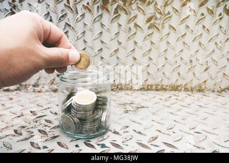 Mettere mano alle monete in un barattolo di vetro con targhetta diamante sfondo. La traduzione del testo in moneta è " Thailandia, 10 bagno'. (Baht è una moneta di Thailandia) Foto Stock