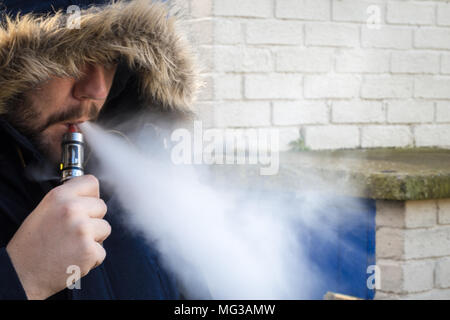 L'uomo vaping, vape cloud con cappa su Foto Stock