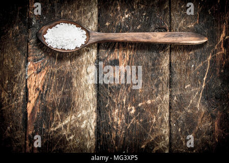 Sale in un cucchiaio di legno. Su sfondo di legno. Foto Stock