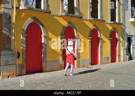 Donna passando un edificio storico con facciata di colore giallo e rosso porte Foto Stock