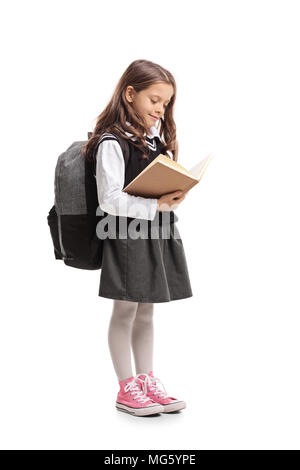 Lunghezza piena ripresa di profilo di un little schoolgirl leggendo un libro isolato su sfondo bianco Foto Stock
