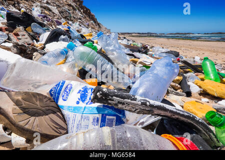 Bottiglie di plastica e di altri rifiuti / inquinamento su una spiaggia in Marocco con il mare in lontananza Foto Stock