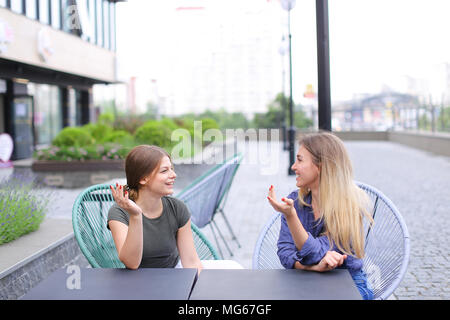 Happy amici di sesso femminile seduto alla street cafe all'esterno. Concetto di avere del tempo libero e aperto. Foto Stock